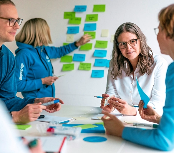 Fünf Personen führen einen Workshop durch und sammeln Informationen auf Notizzetteln.