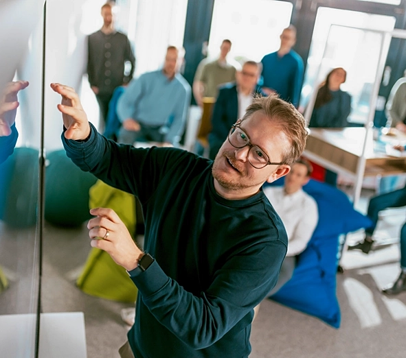 Ein Mann präsentiert Informationen und bedient dabei einen interaktiven Bildschirm.