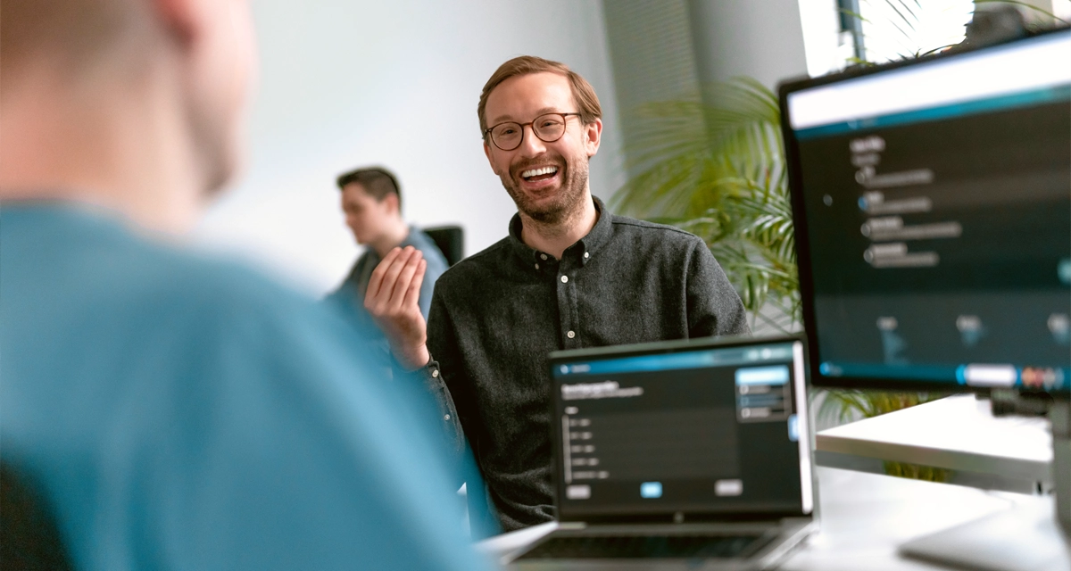 Zwei Personen sitzen sich am Arbeitsplatz gegenüber und unterhalten sich