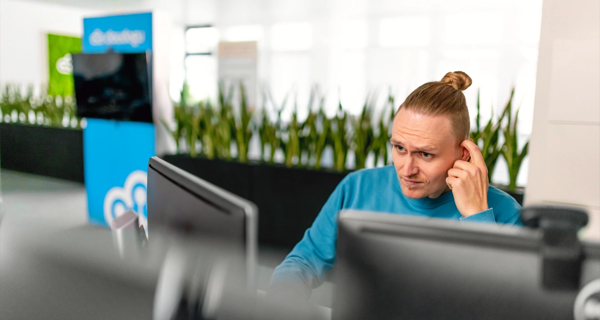 Eine Person sitzt an einem Computerarbeitsplatz und denkt über eine Aufgabe nach